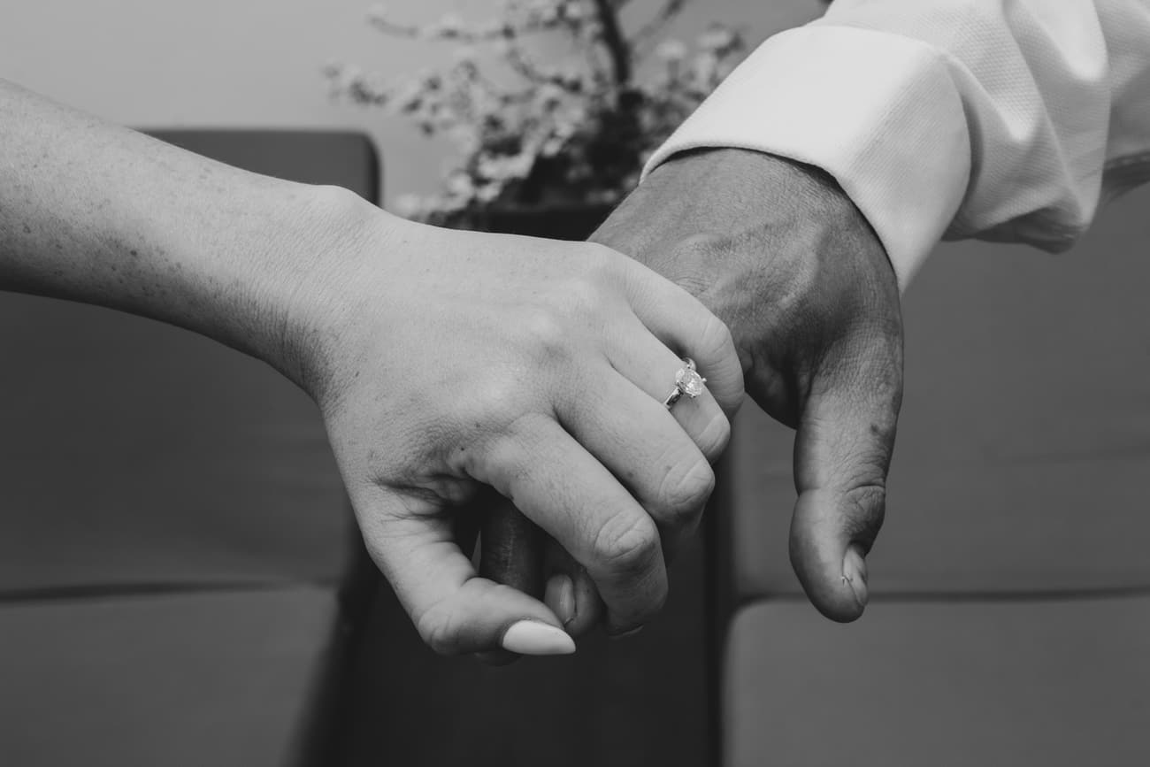 Odette and Morné holding hands, her engagement ring catching the light.